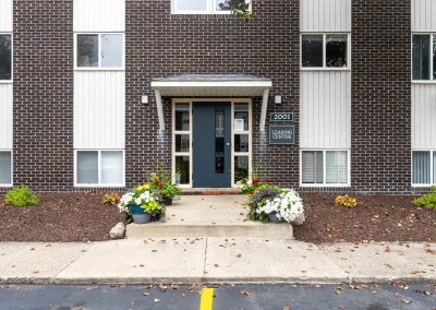 Close-up of a residential building entrance at Arbor Hills Apartments with landscaped flower beds