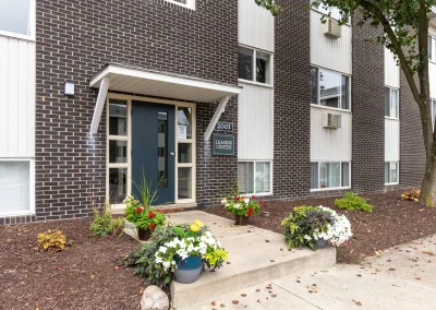 Close-up of a residential building entrance at Arbor Hills Apartments with landscaped flower beds