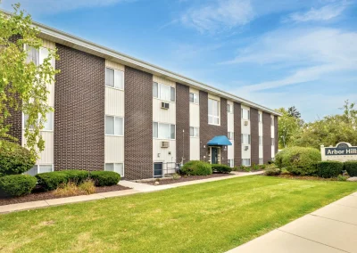 Wide view of Arbor Hills Apartments buildings with green lawns and mature trees on a sunny day