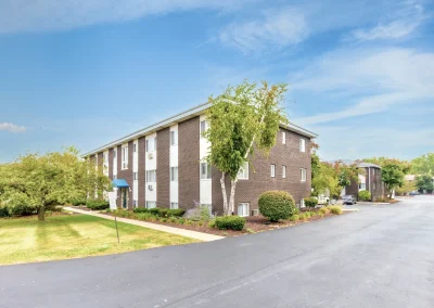 Exterior of Arbor Hills Apartments with parking area and residential buildings in the background